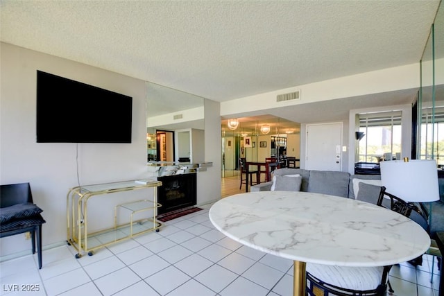dining area featuring light tile patterned flooring, visible vents, and a textured ceiling