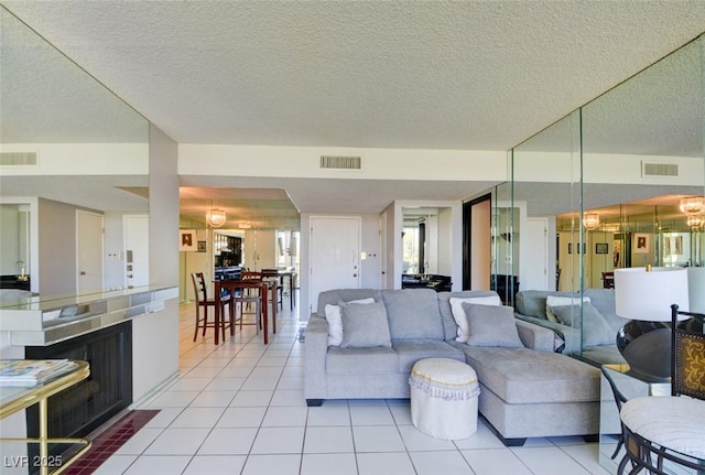 living room featuring light tile patterned floors, visible vents, and a notable chandelier