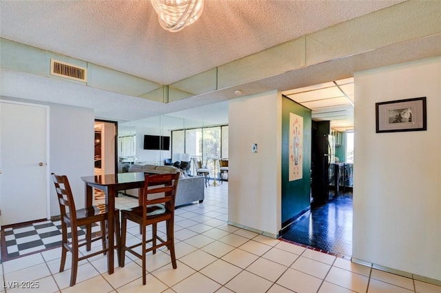 dining space with light tile patterned floors, visible vents, and a textured ceiling