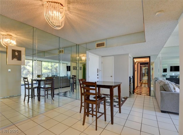 dining room featuring a chandelier, visible vents, a textured ceiling, and light tile patterned flooring