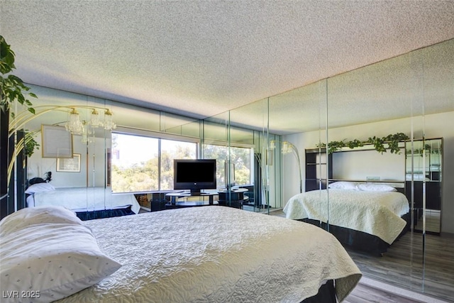 bedroom featuring a chandelier, multiple windows, a textured ceiling, and wood finished floors