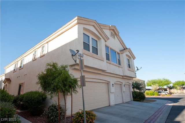 view of side of property with stucco siding, driveway, and a garage