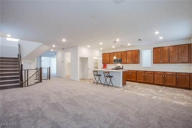 5748 Avondale Rise Way, Las Vegas, NV 89141 - kitchen featuring appliances with stainless steel finishes, light carpet, open floor plan, brown cabinets, and recessed lighting