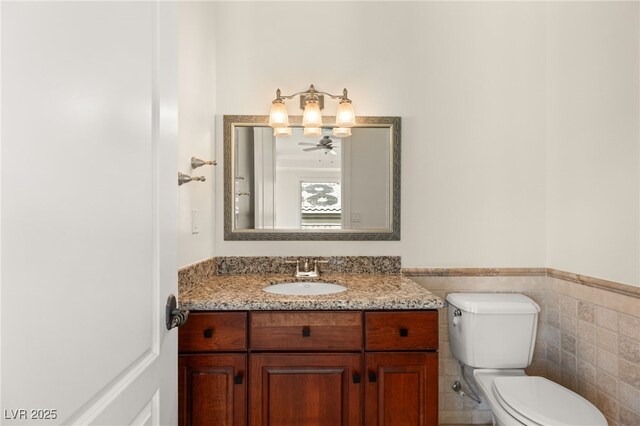 2660 Mirabella St, Henderson, NV 89052 - half bath featuring wainscoting, toilet, vanity, and tile walls