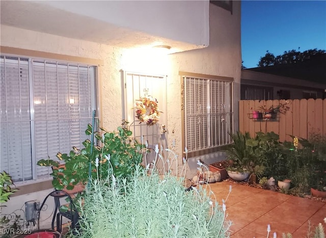 view of side of home featuring stucco siding and fence
