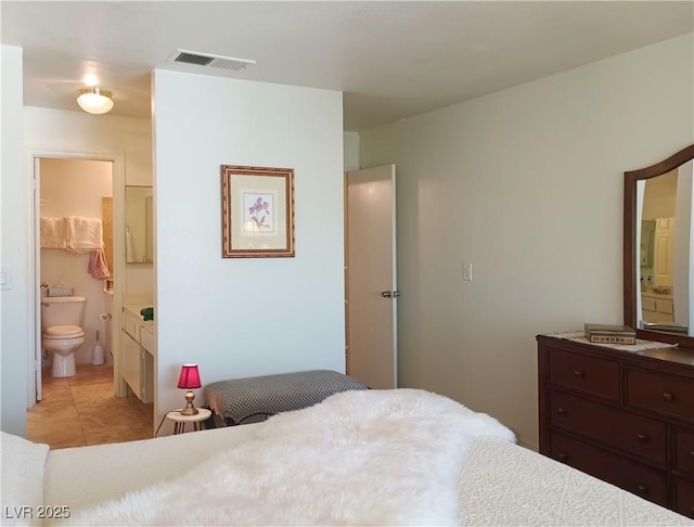 bedroom with ensuite bathroom, visible vents, and light tile patterned floors