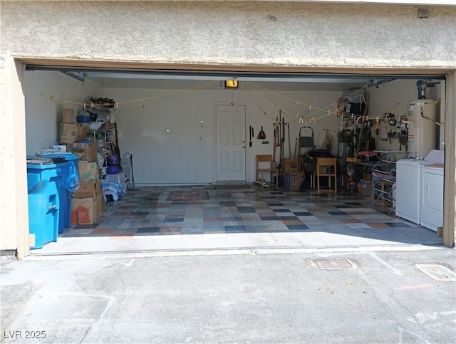 garage with water heater, washer and clothes dryer, and a garage door opener