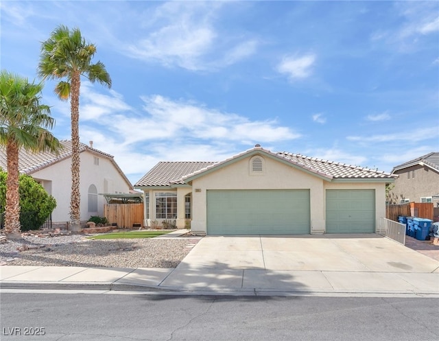 mediterranean / spanish-style home with concrete driveway, fence, a garage, and stucco siding