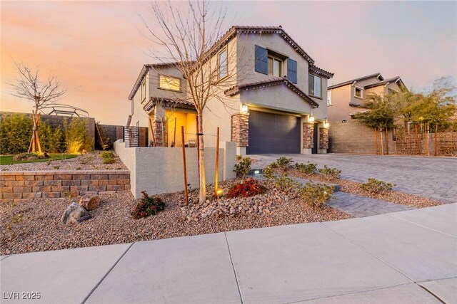 view of front of house featuring stucco siding, driveway, a fenced front yard, an attached garage, and a tiled roof