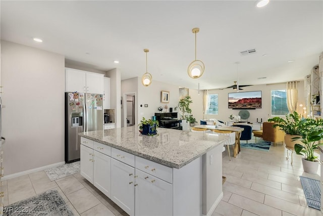 kitchen featuring light stone countertops, a kitchen island, white cabinets, and stainless steel fridge with ice dispenser