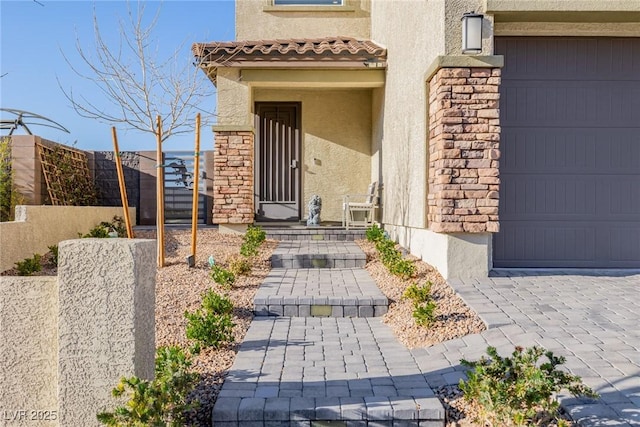 doorway to property with a garage and stucco siding