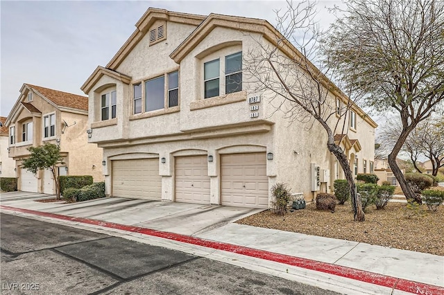 multi unit property with a garage, driveway, and stucco siding