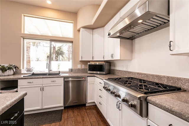 kitchen with exhaust hood, a sink, appliances with stainless steel finishes, recessed lighting, and white cabinetry