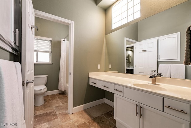 full bathroom featuring baseboards, toilet, shower / bathtub combination with curtain, vanity, and stone tile floors