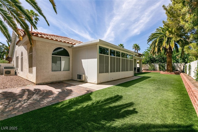 rear view of property featuring stucco siding, a patio area, a fenced backyard, a yard, and a tiled roof