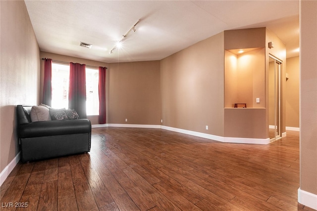 living area featuring visible vents, hardwood / wood-style flooring, baseboards, and track lighting