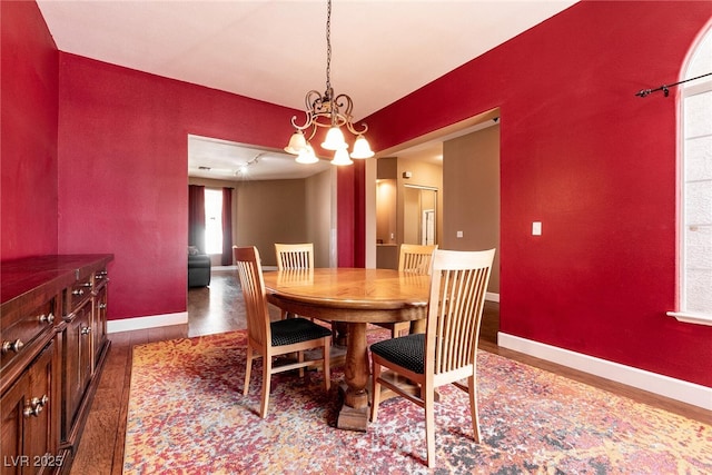 dining room featuring baseboards, an inviting chandelier, and wood finished floors