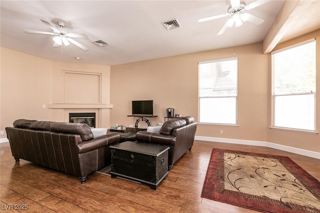 living area featuring baseboards, wood-type flooring, a ceiling fan, and visible vents