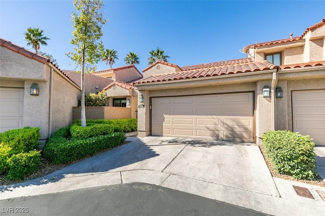 view of front of house with stucco siding, driveway, a tiled roof, and an attached garage