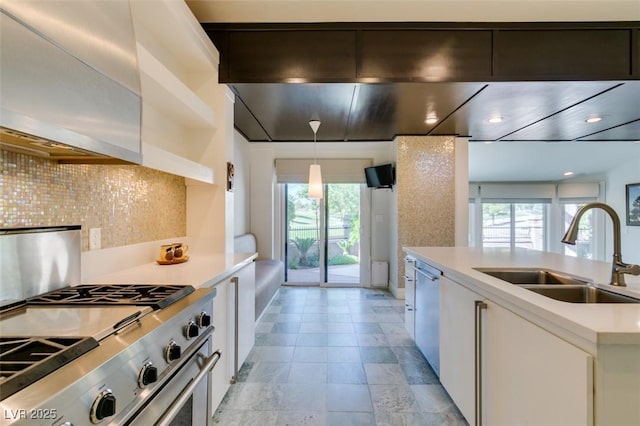 kitchen with a sink, decorative backsplash, white cabinetry, light countertops, and appliances with stainless steel finishes