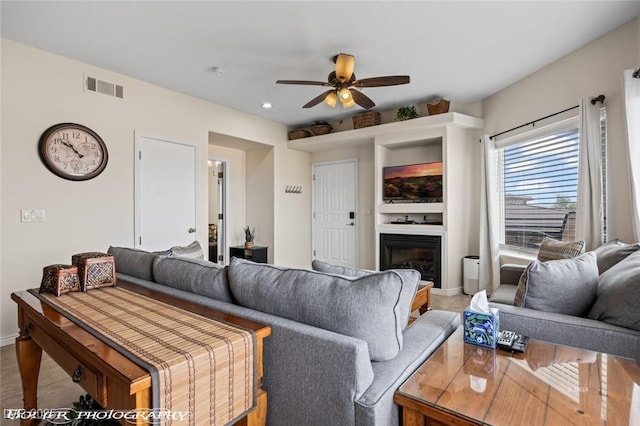 405 Paradise Pkwy Unit 170, Mesquite, NV 89027 - living area with a glass covered fireplace, a ceiling fan, visible vents, and baseboards