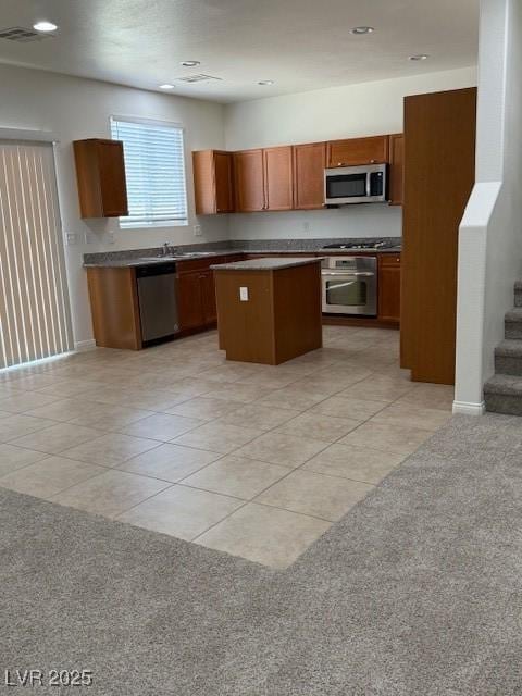 3104 Naggio Shores Ave, Las Vegas, NV 89141 - kitchen with appliances with stainless steel finishes, a kitchen island, light tile patterned floors, brown cabinets, and dark countertops