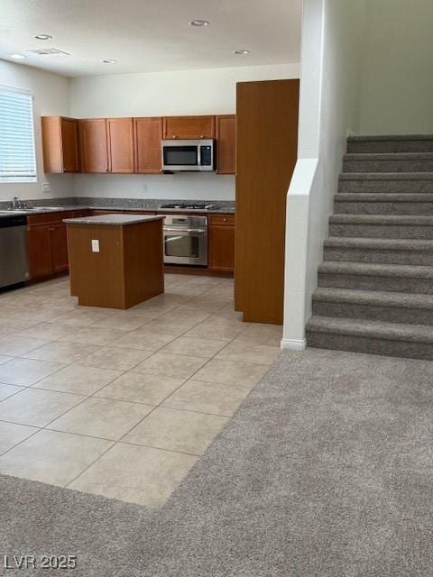 3104 Naggio Shores Ave, Las Vegas, NV 89141 - kitchen featuring appliances with stainless steel finishes, a kitchen island, light tile patterned flooring, brown cabinets, and dark countertops