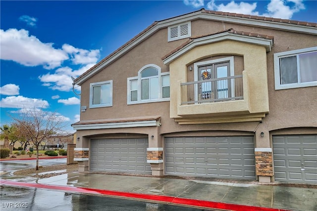 townhome / multi-family property with a garage, stucco siding, and a balcony