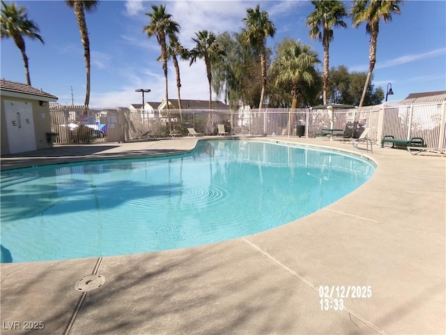 pool with a patio area and fence