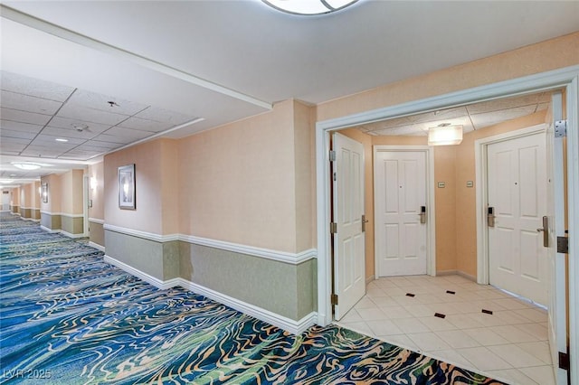 hall with baseboards and a paneled ceiling