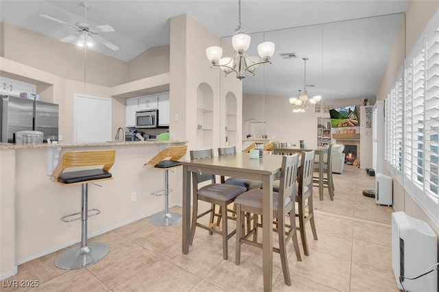 5000 Red Rock St Unit 241, Las Vegas, NV 89118 - dining area featuring a chandelier, light tile patterned flooring, ceiling fan, and a warm lit fireplace