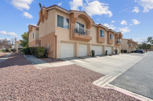 5000 Red Rock St Unit 241, Las Vegas, NV 89118 - view of front of home with stucco siding, an attached garage, driveway, a residential view, and a balcony