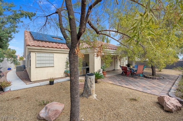 8217 Ashkum Ave, Las Vegas, NV 89149 - view of front facade with a tiled roof, stucco siding, roof mounted solar panels, and a patio area
