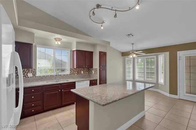 8217 Ashkum Ave, Las Vegas, NV 89149 - kitchen featuring a sink, lofted ceiling, white fridge, light tile patterned floors, and decorative backsplash