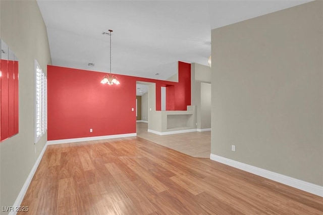 8217 Ashkum Ave, Las Vegas, NV 89149 - unfurnished living room featuring light wood-style floors, vaulted ceiling, a chandelier, and baseboards