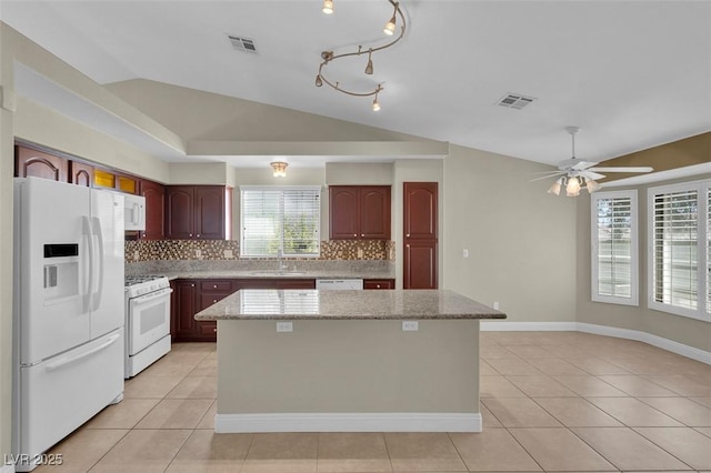 8217 Ashkum Ave, Las Vegas, NV 89149 - kitchen with white appliances, vaulted ceiling, backsplash, a kitchen island, and light tile patterned floors