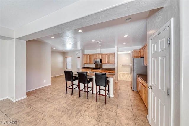 2528 Flodden St, Henderson, NV 89044 - kitchen featuring baseboards, recessed lighting, light tile patterned flooring, a kitchen bar, and appliances with stainless steel finishes