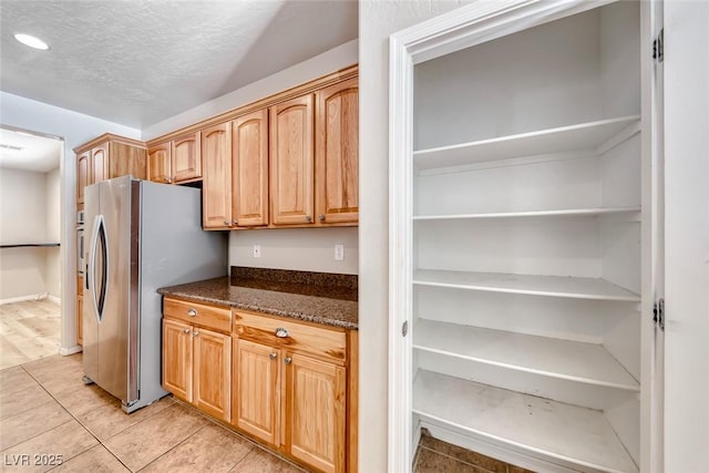 2528 Flodden St, Henderson, NV 89044 - kitchen featuring stainless steel fridge with ice dispenser, a textured ceiling, recessed lighting, dark stone counters, and light tile patterned flooring