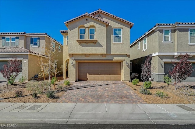 view of front facade with stucco siding, decorative driveway, and a garage