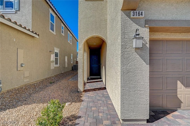 view of exterior entry with stucco siding and a garage