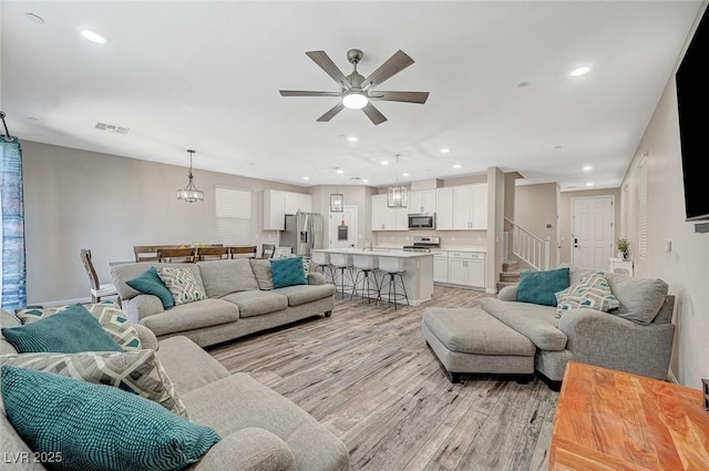 living room with visible vents, a ceiling fan, recessed lighting, stairway, and light wood-style floors