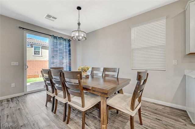 dining area with a notable chandelier, visible vents, light wood-type flooring, and baseboards