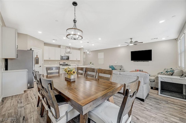 dining space with ceiling fan with notable chandelier, recessed lighting, light wood-style floors, and visible vents
