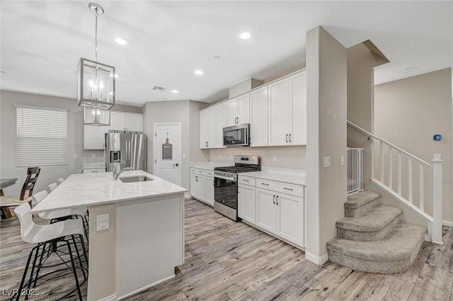kitchen with a sink, a breakfast bar area, appliances with stainless steel finishes, and light wood-style flooring
