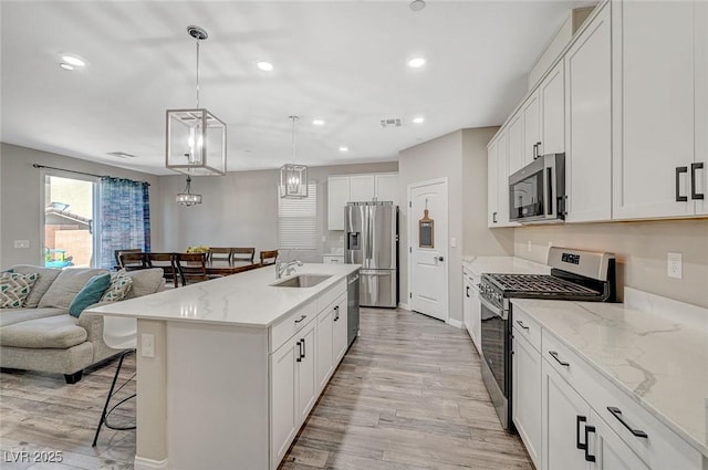 kitchen featuring open floor plan, recessed lighting, light wood-style flooring, appliances with stainless steel finishes, and a kitchen breakfast bar
