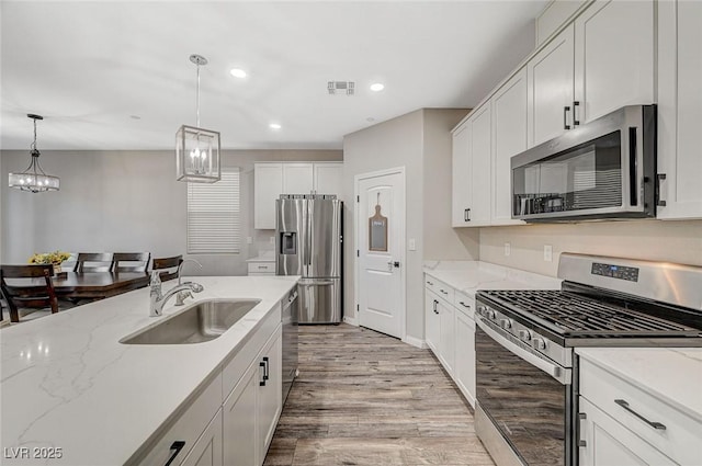 kitchen with visible vents, a sink, light wood-style floors, appliances with stainless steel finishes, and white cabinets