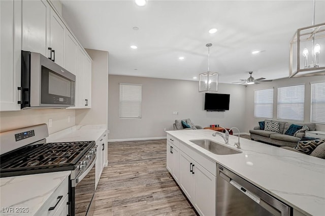 kitchen featuring a sink, white cabinets, open floor plan, and stainless steel appliances