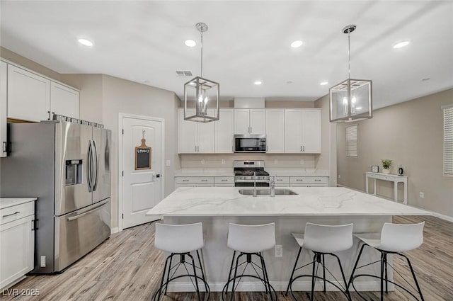 kitchen with visible vents, light wood-style flooring, appliances with stainless steel finishes, white cabinets, and a sink