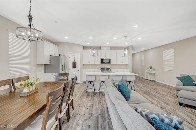 dining room featuring recessed lighting, light wood-type flooring, baseboards, and a notable chandelier