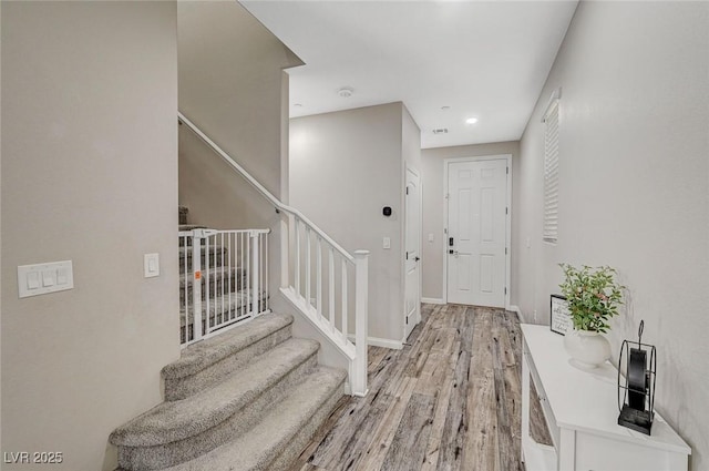 foyer featuring visible vents, baseboards, stairs, and light wood finished floors
